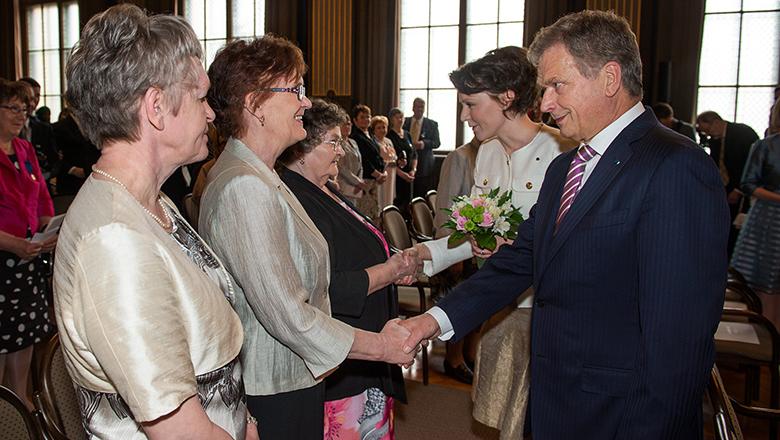 Suomen tasavallan presidentti Sauli Niinistö ja puoliso Jenni Haukio kättelevät äitienpäivänä palkittuja naisia.